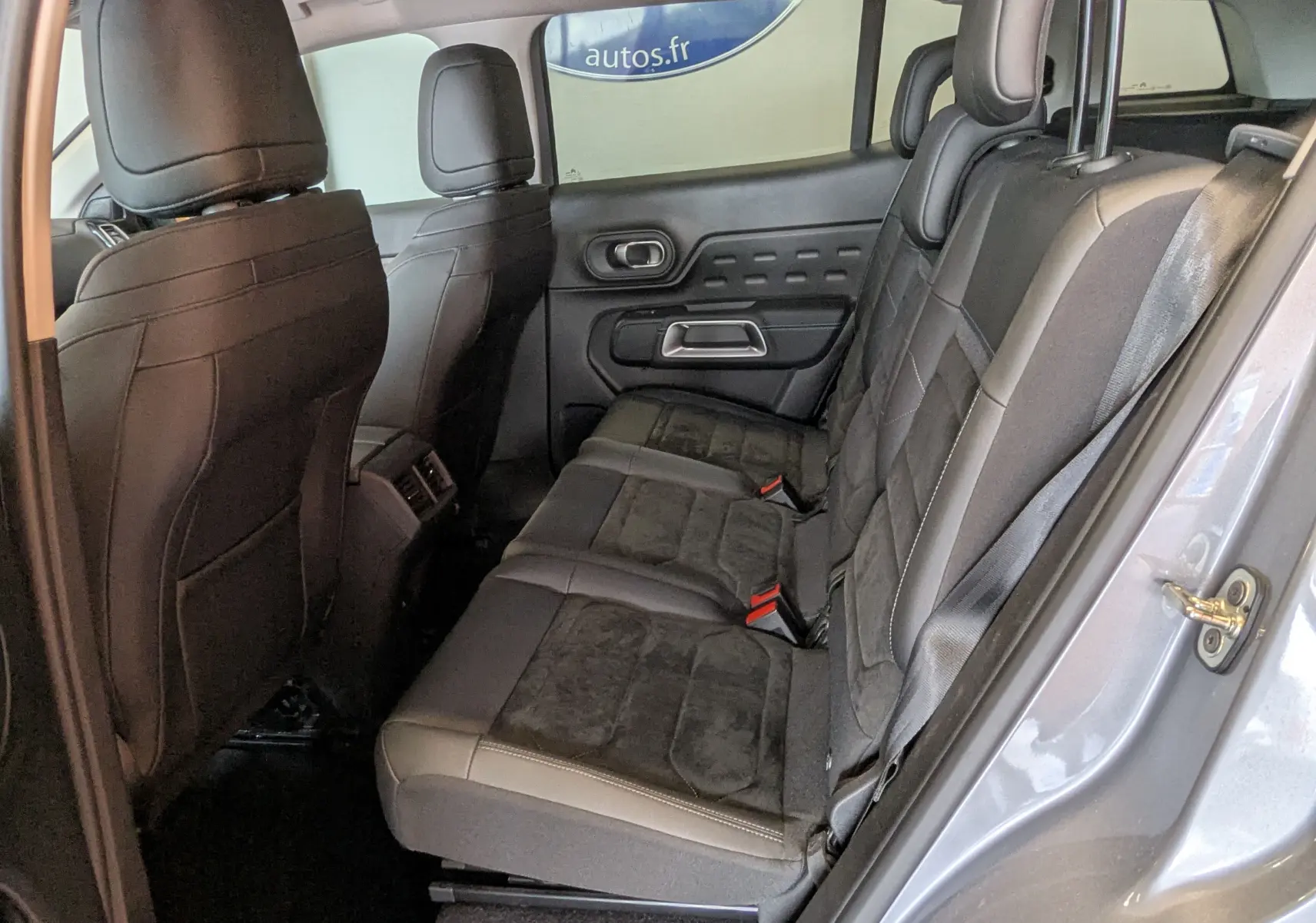 Vue intérieure côté droit des sièges arrière en cuir noir du Citroën C5 Aircross gris Artens 2024, avec détails de la porte.