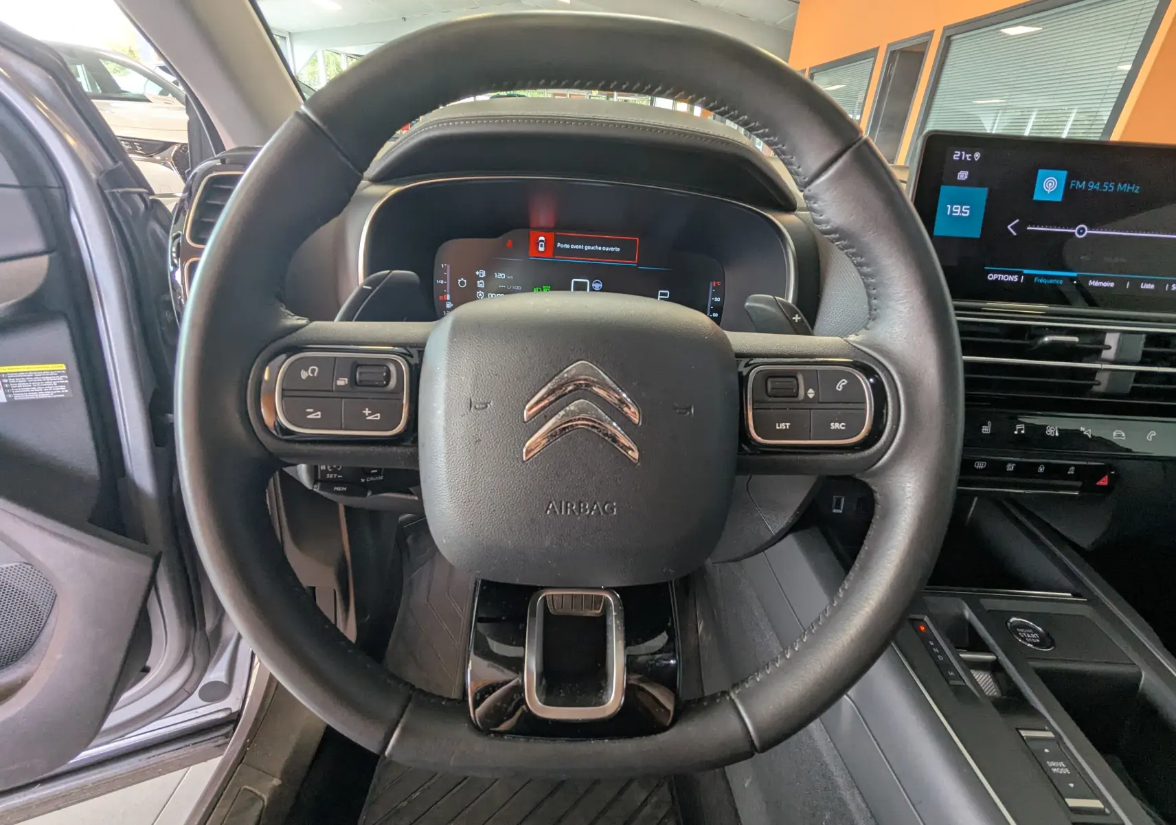 Vue intérieure centrée sur le volant noir du Citroën C5 Aircross 2024 avec tableau de bord numérique et écran tactile.