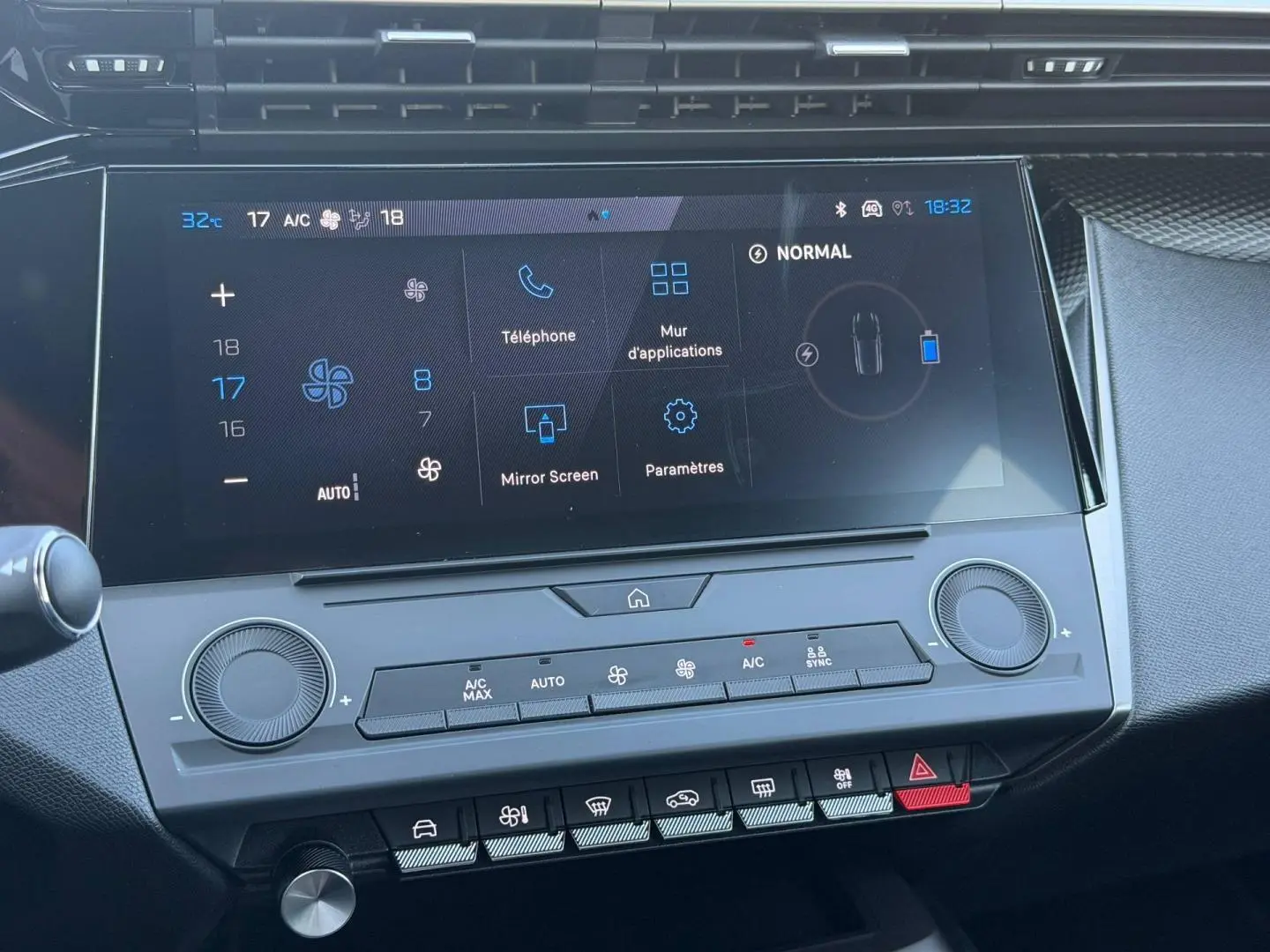 Vue rapprochée de l’écran tactile central et des commandes de climatisation de la Peugeot e-308 noire, intérieur moderne et épuré.