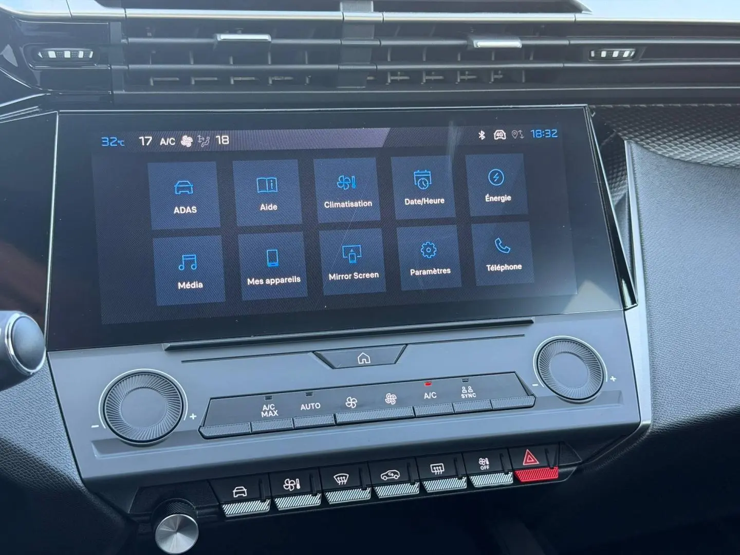 Vue rapprochée de l’écran tactile central et des commandes de climatisation de la Peugeot e-308 noire, intérieur moderne.