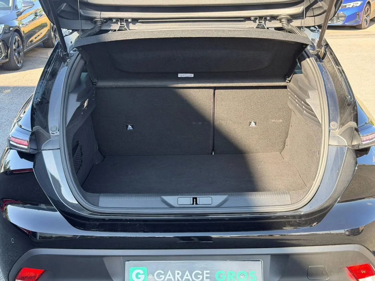 Coffre ouvert vu de l'arrière d'une Peugeot 308 e-308 noire Perla Nera, montrant l'espace de chargement vide.