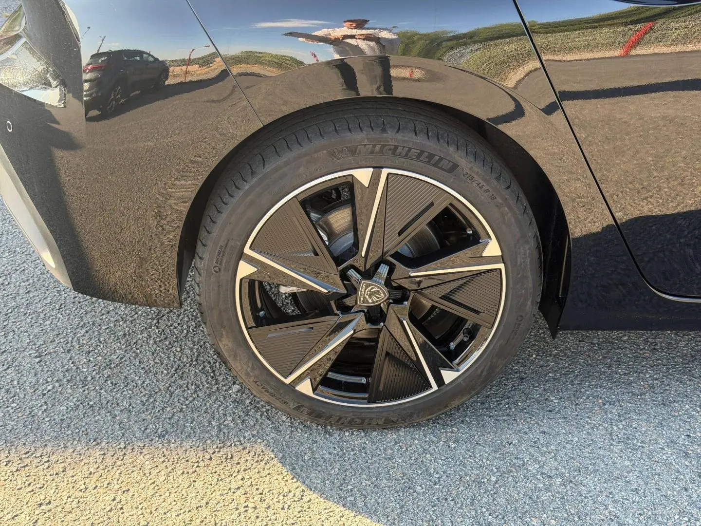 Gros plan sur la roue arrière droite de la Peugeot e-308 noire Perla Nera avec jante alu au design moderne.