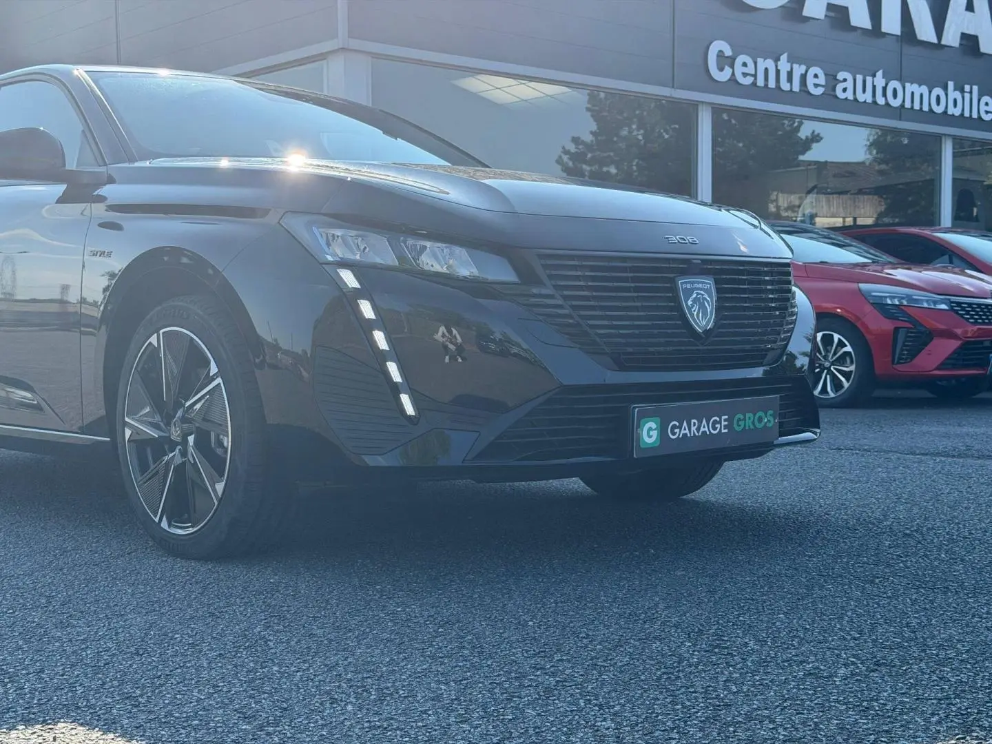 Peugeot e-308 noir Perla Nera vue 3/4 avant avec calandre noire et feux LED verticaux allumés.