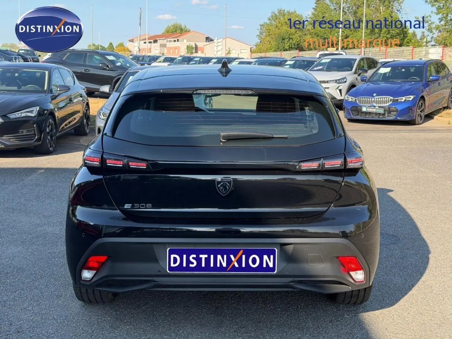 Vue arrière d'une Peugeot e-308 noire Perla Nera avec feux LED distinctifs et logo lion central.