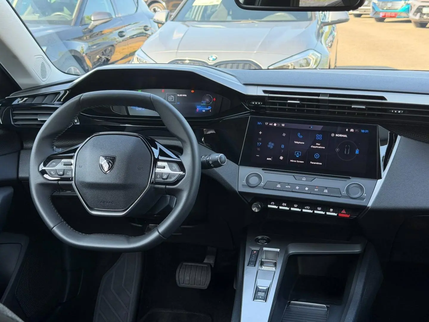 Vue intérieure avant du tableau de bord et volant noir de la Peugeot e-308 2025 avec écran tactile et commandes au volant.