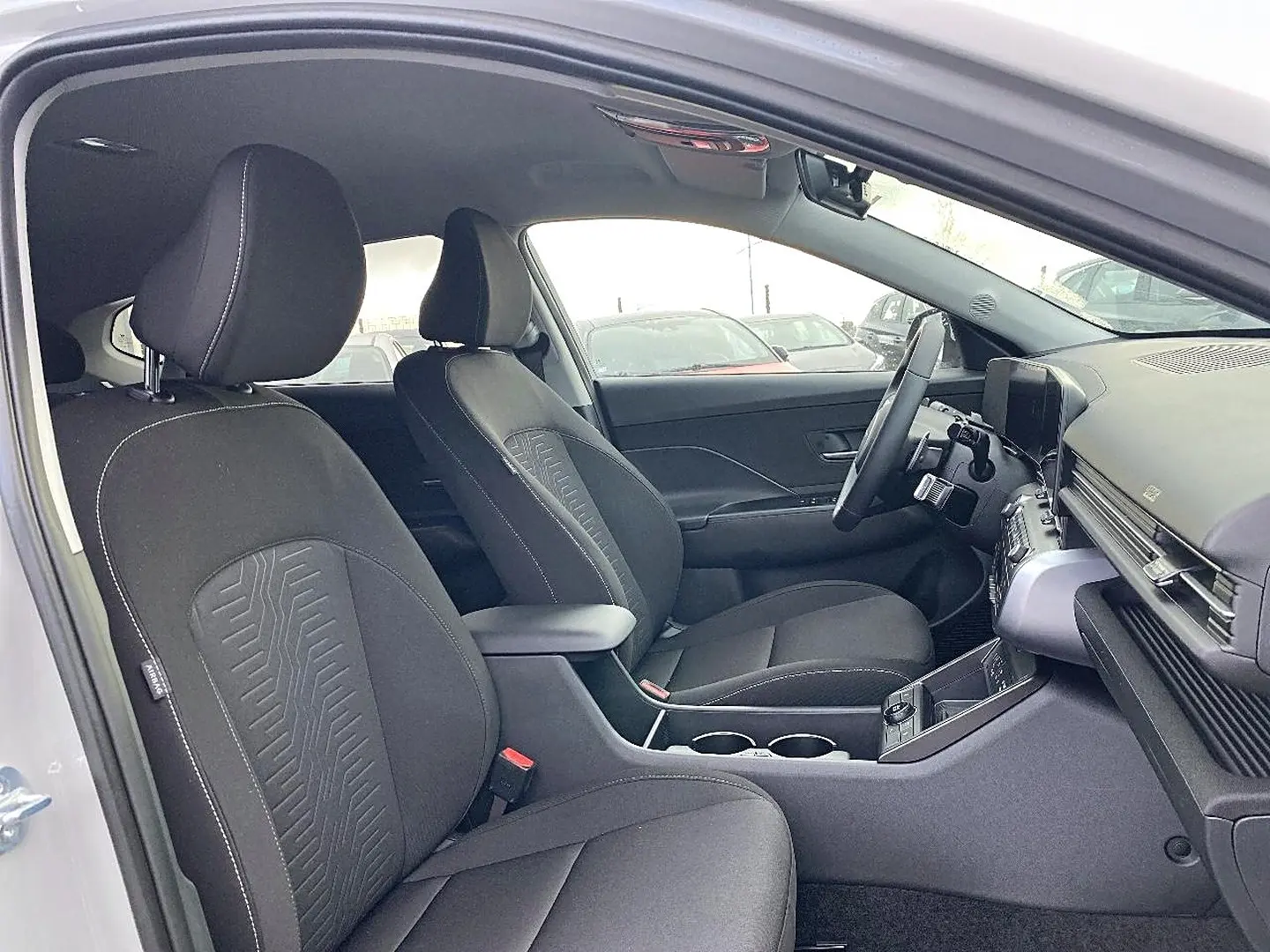 Vue intérieure côté conducteur du Hyundai Kona 2025 gris, montrant sièges avant, volant multifonction et console centrale.
