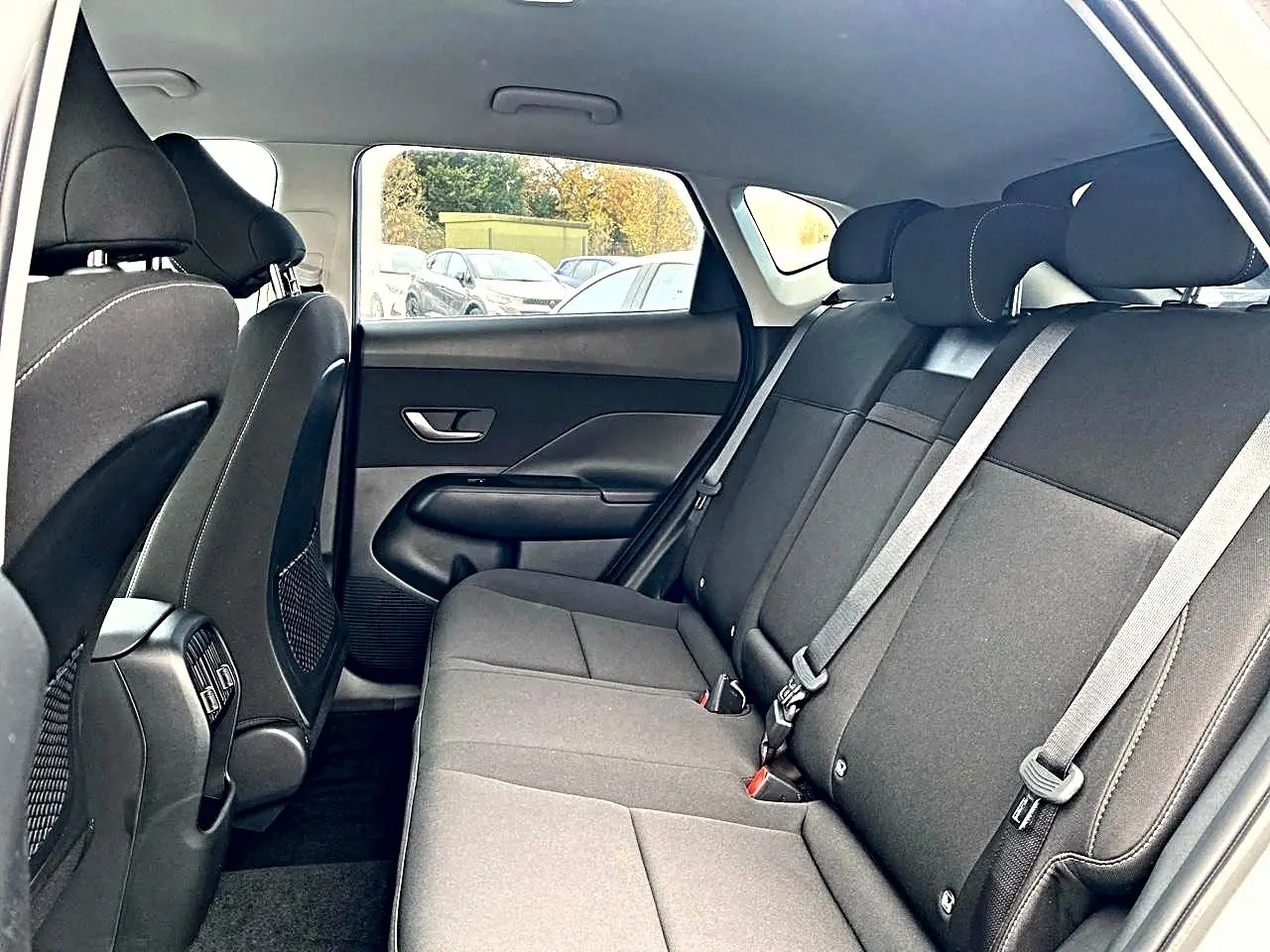 Vue intérieure côté droit de la banquette arrière noire du Hyundai Kona 2025 avec appuie-têtes et ceintures visibles.