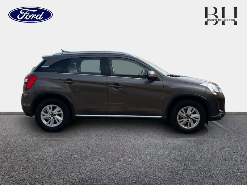 Profil droit d'un Citroën C4 Aircross 2016 brun Mangaro, avec jantes alu et barres de toit visibles.