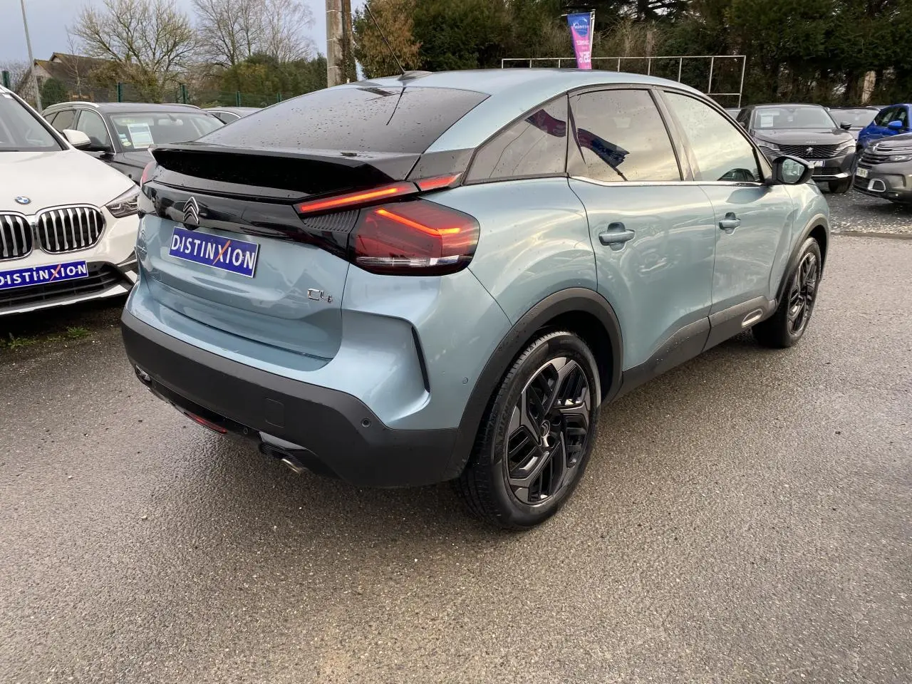 Vue 3/4 arrière droite d'une Citroën C4 bleu Iceland avec feux arrière LED et toit noir brillant.