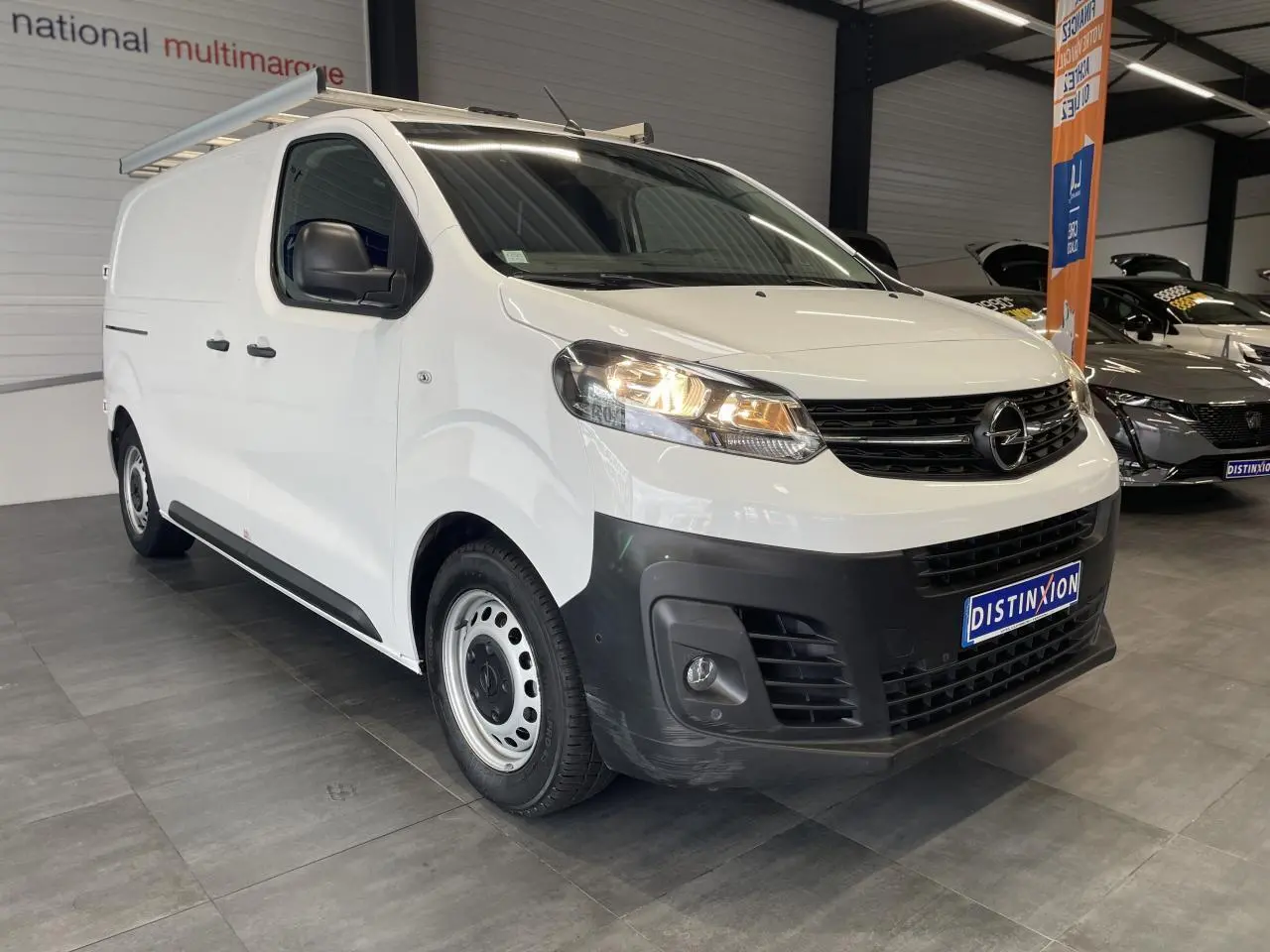 Opel Vivaro blanc en fourgon, vue 3/4 avant droit, avec boucliers noirs et jantes tôles 16 pouces.