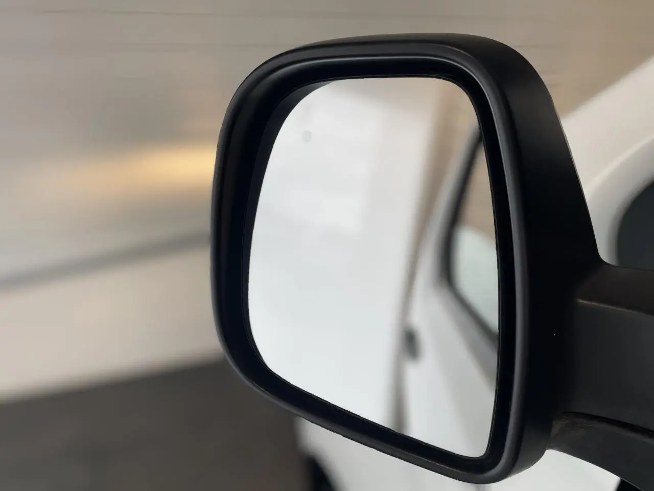 Rétroviseur extérieur droit noir du fourgon blanc Opel Vivaro 2021, vue rapprochée sur fond flou.