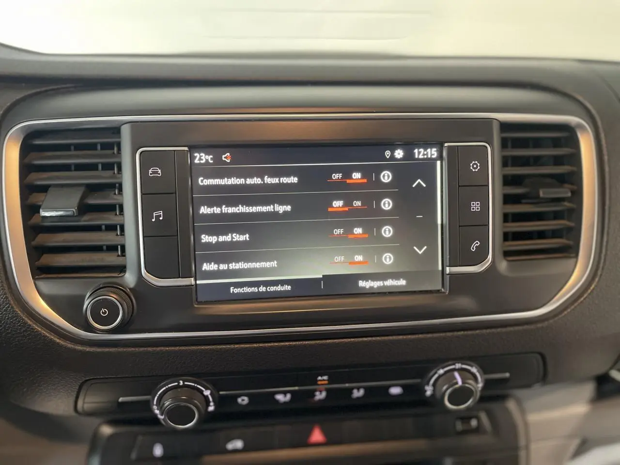 Écran tactile central du tableau de bord noir de l'Opel Vivaro blanc, affichant les réglages d'aides à la conduite.