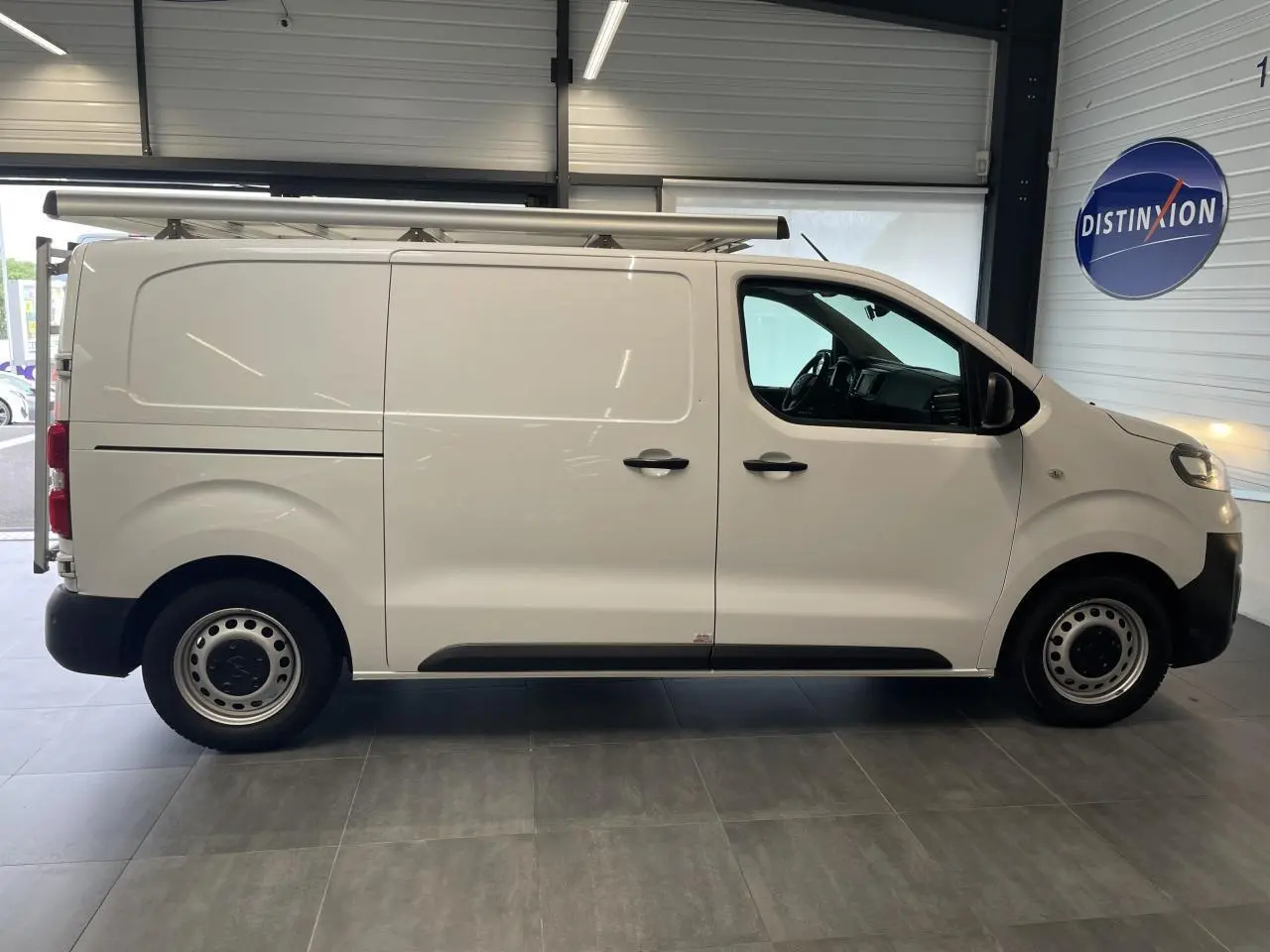 Opel Vivaro blanc en vue profil côté gauche, fourgon utilitaire avec porte latérale coulissante et jantes tôle.
