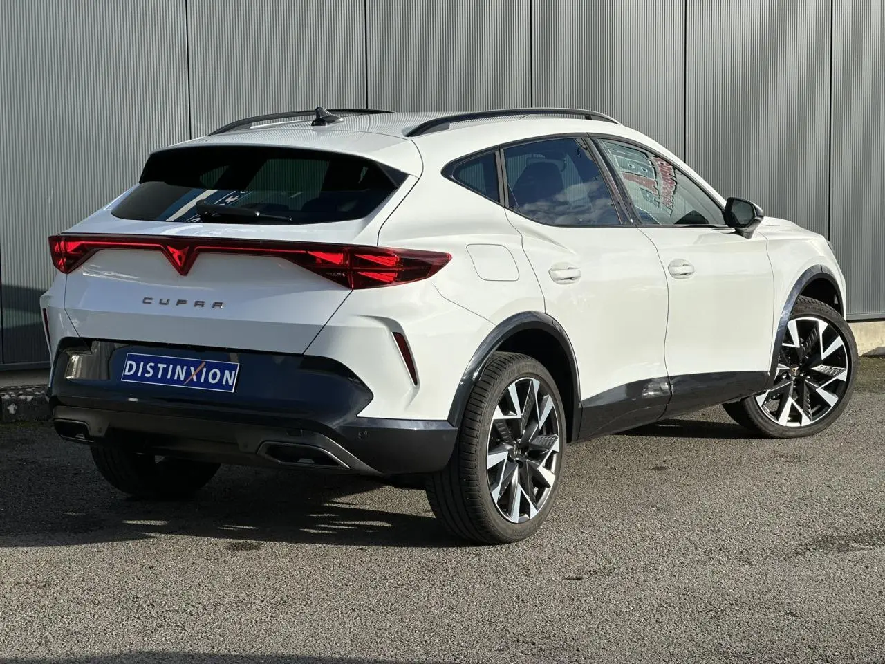 Vue 3/4 arrière droite d'une CUPRA Formentor blanche avec feux arrière en bandeau lumineux et jantes alliage noires et argent.