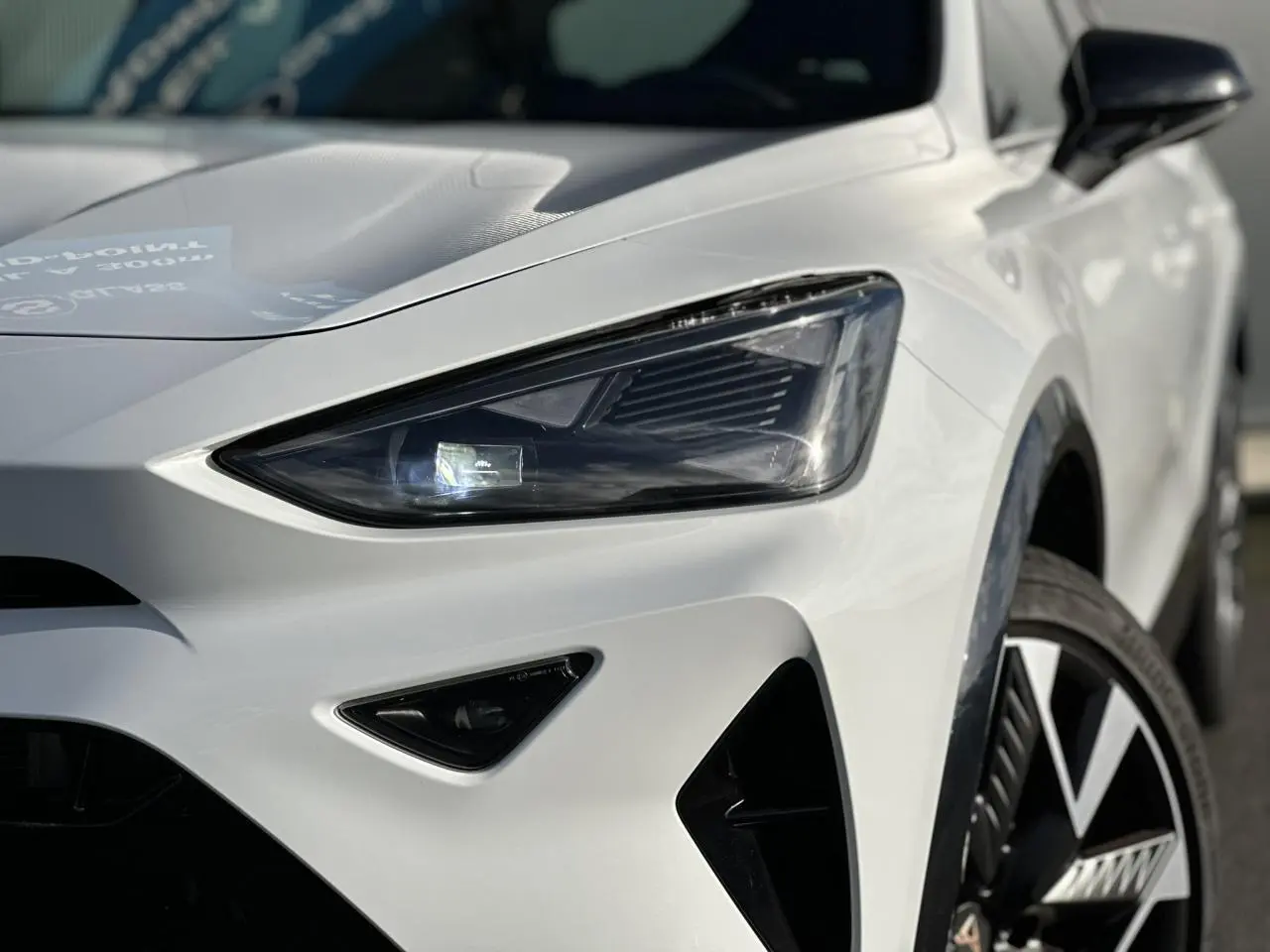 Gros plan sur l'avant droit blanc du CUPRA Formentor 2025, mettant en valeur son phare LED et la jante alliage distinctive.
