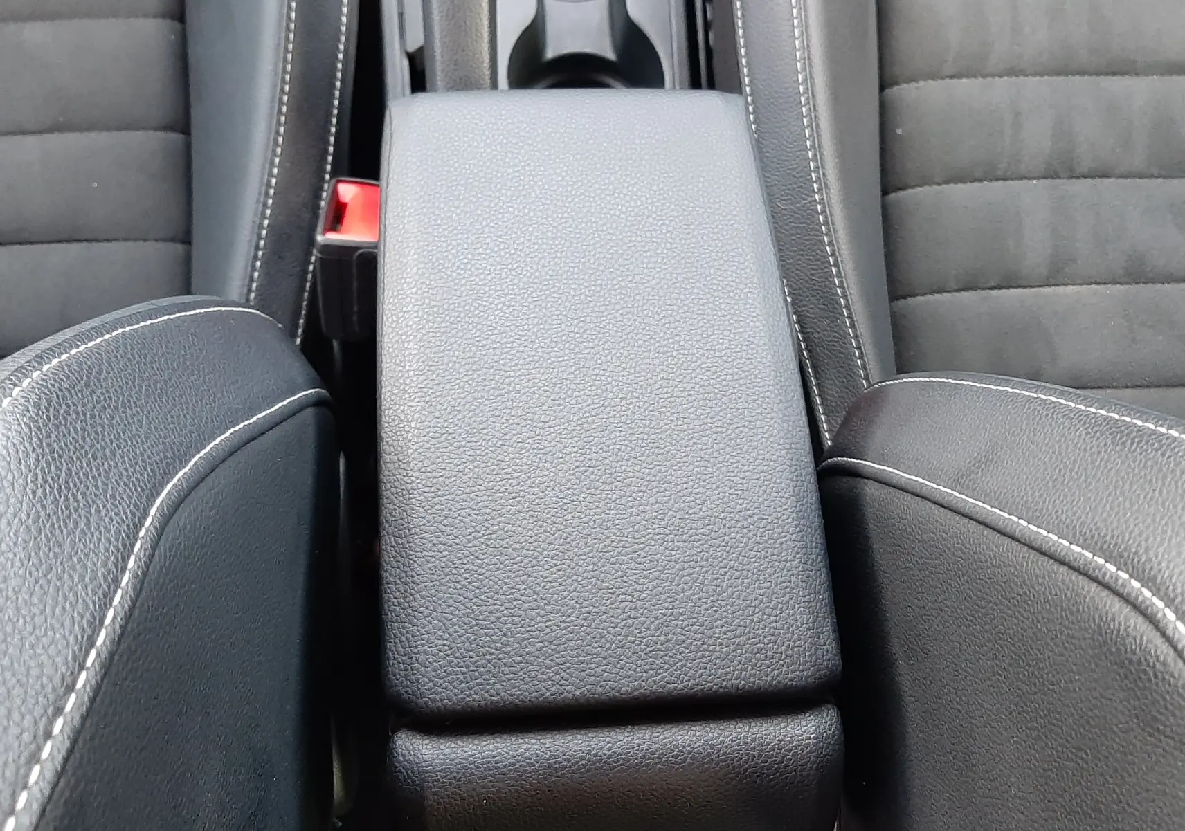 Gros plan sur l'accoudoir central en cuir noir avec surpiqûres blanches entre les sièges avant du SEAT Arona 2025.