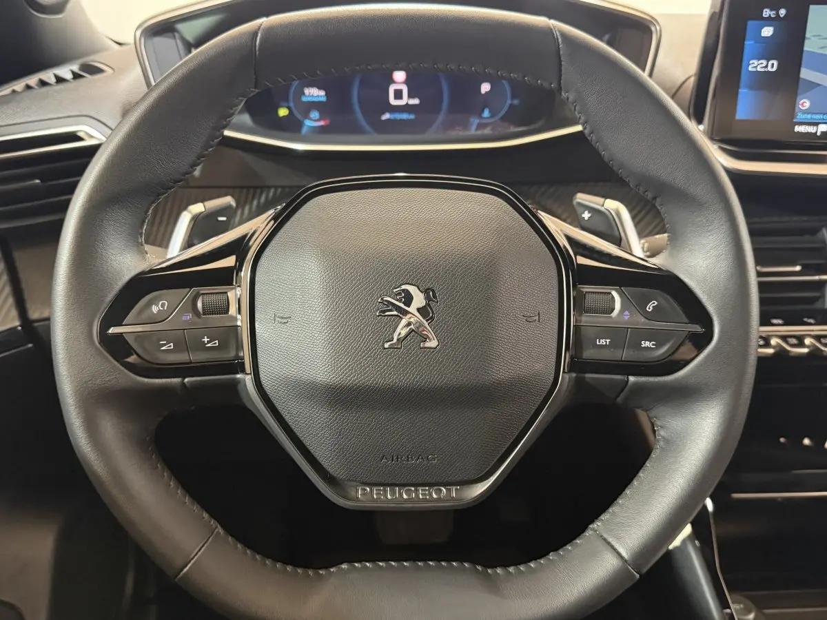 Vue rapprochée du volant cuir noir du Peugeot 2008 2023 avec commandes multifonctions et tableau de bord digital.