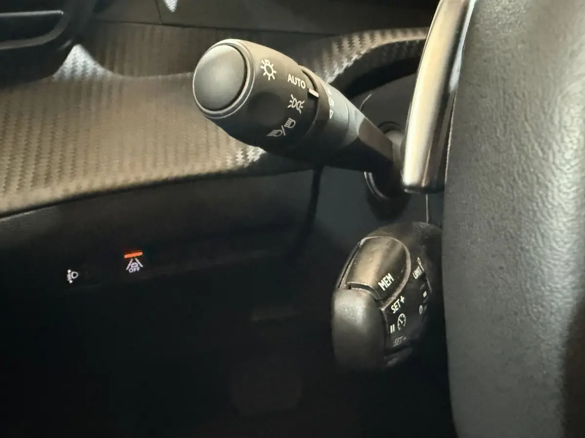 Gros plan sur les commandes au volant du Peugeot 2008 gris clair, avec levier d'éclairage et régulateur de vitesse.