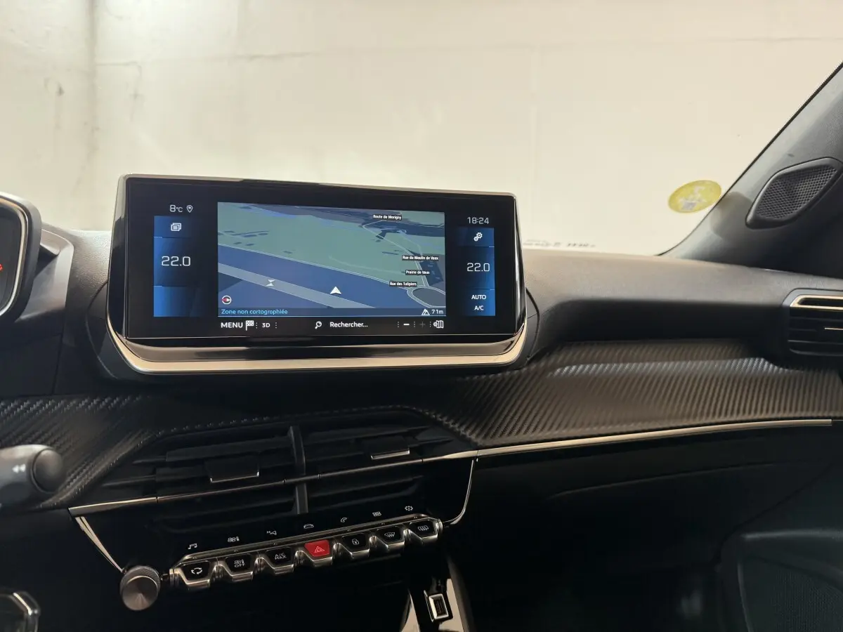 Vue intérieure du tableau de bord du Peugeot 2008 gris clair, avec écran tactile central affichant la navigation.
