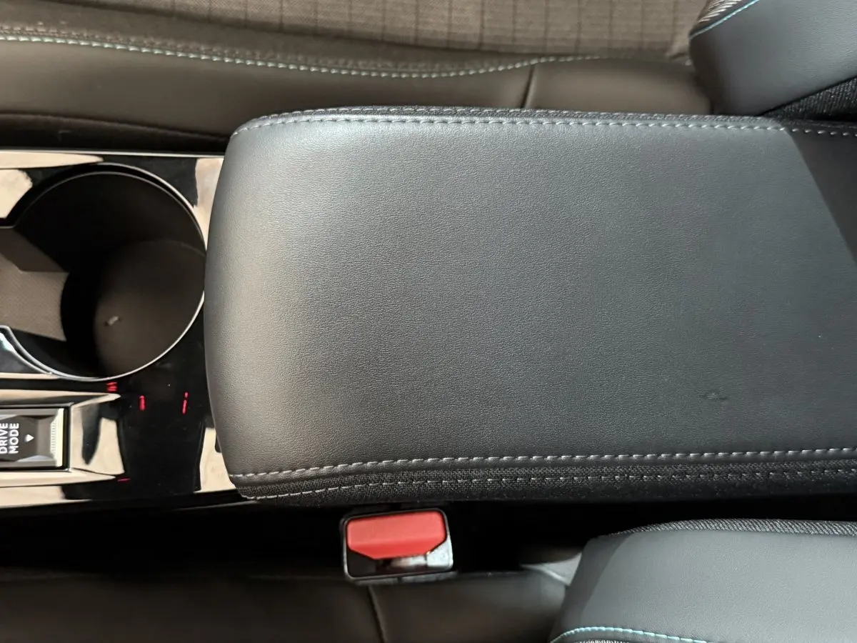 Gros plan intérieur sur l'accoudoir central noir et la console avec porte-gobelet de la Peugeot 2008 gris clair.