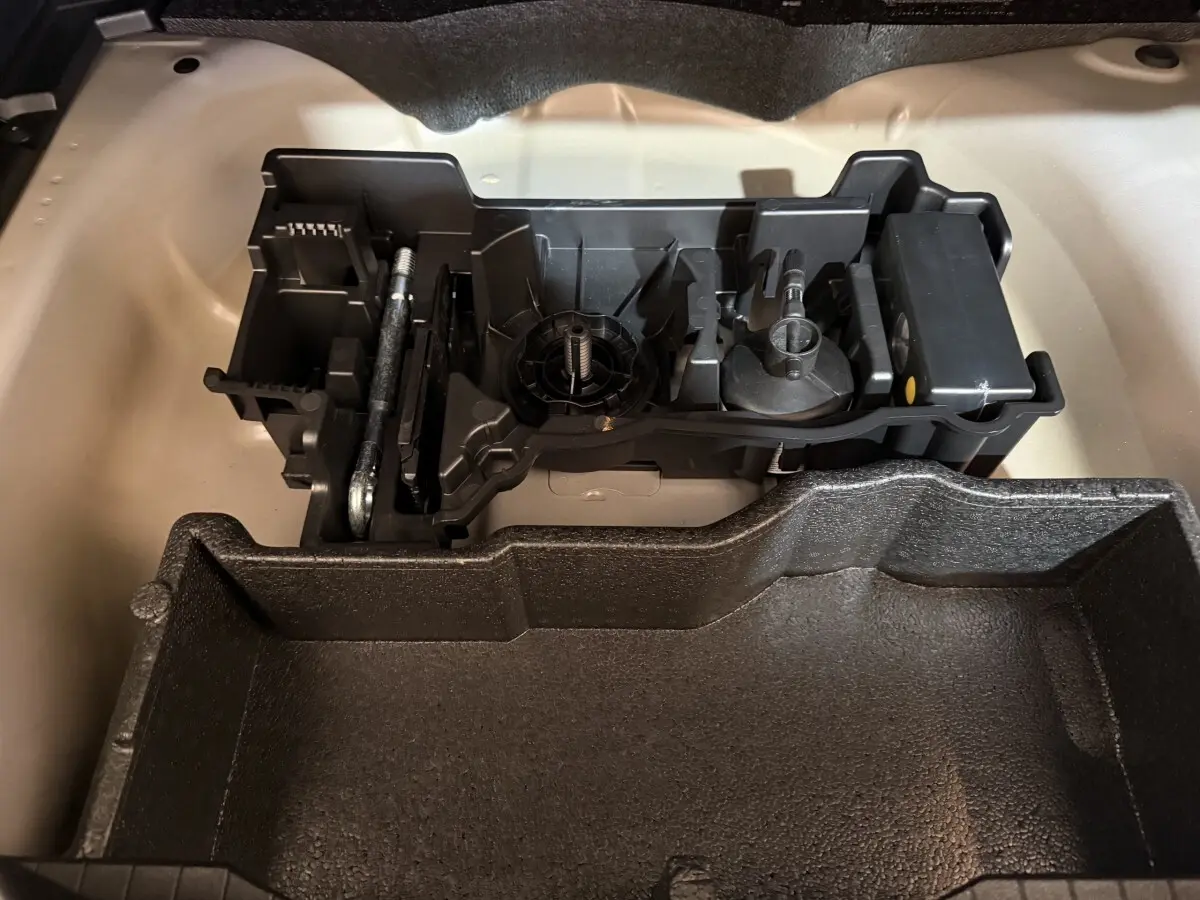 Compartiment de rangement sous le coffre du Peugeot 2008 gris clair, montrant l'organisation des outils et accessoires.