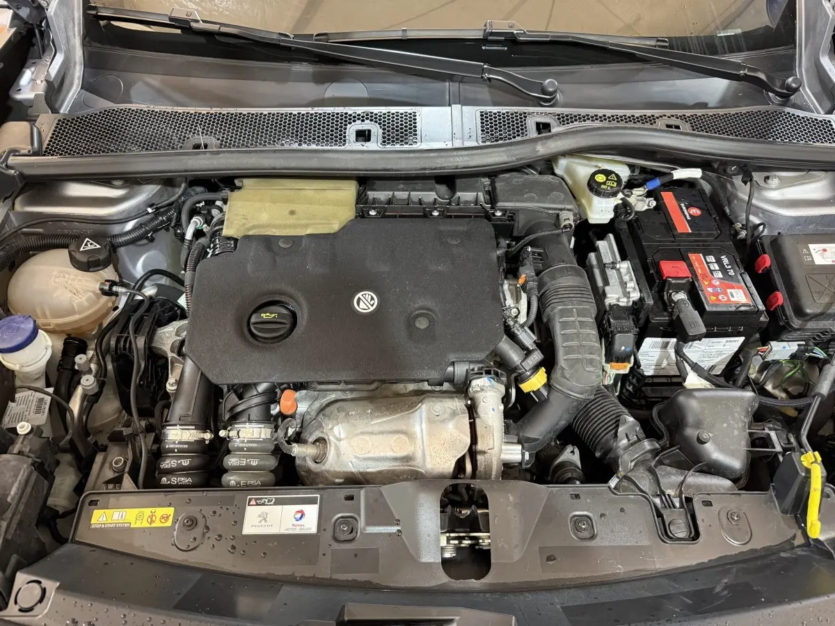 Vue plongeante sur le moteur diesel gris clair du Peugeot 2008 2023, avec batterie et composants visibles.