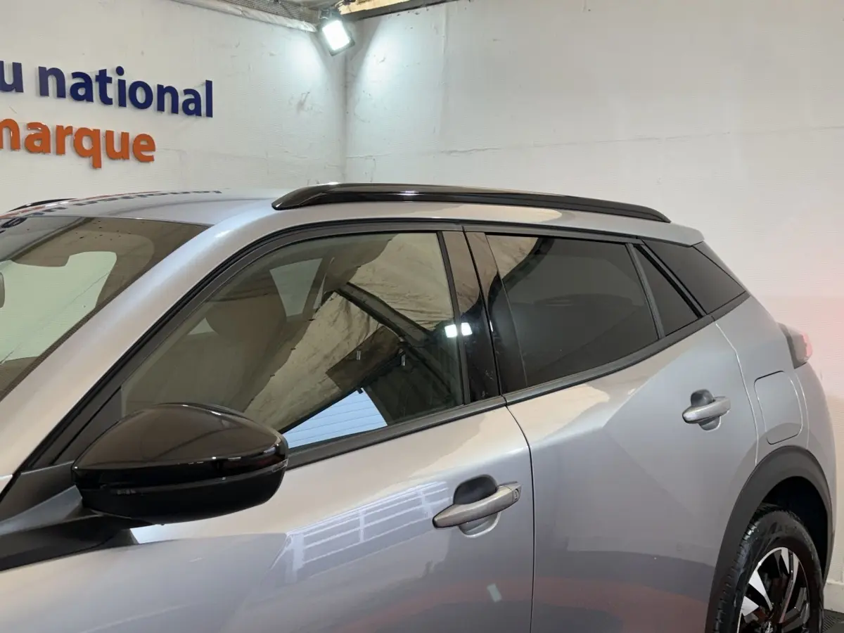 Vue latérale droite du Peugeot 2008 gris clair 2023 avec rétroviseur noir et toit ouvrant panoramique.