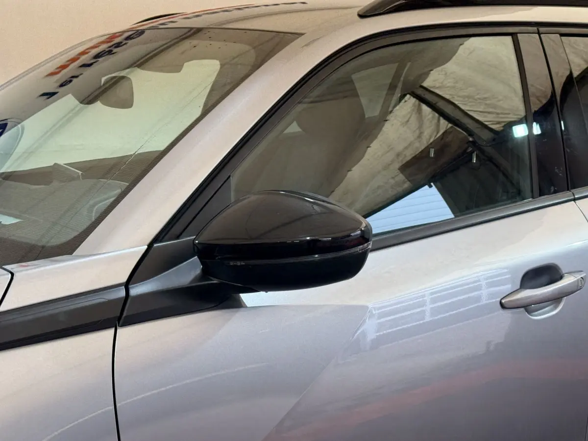 Détail du rétroviseur noir côté conducteur sur la porte gris clair d’un Peugeot 2008 2023.