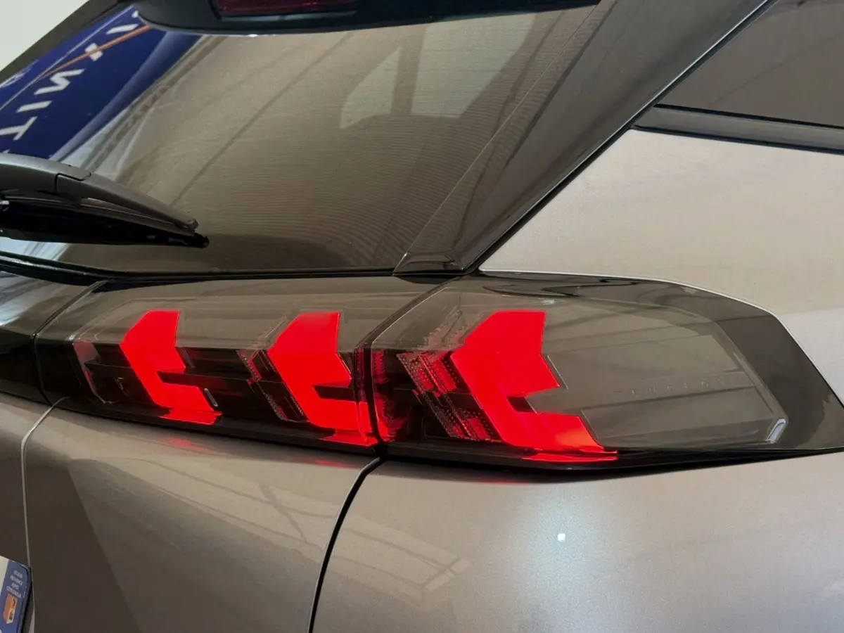 Gros plan sur le feu arrière droit rouge vif d’un Peugeot 2008 gris clair 2023, avec vitrage teinté.