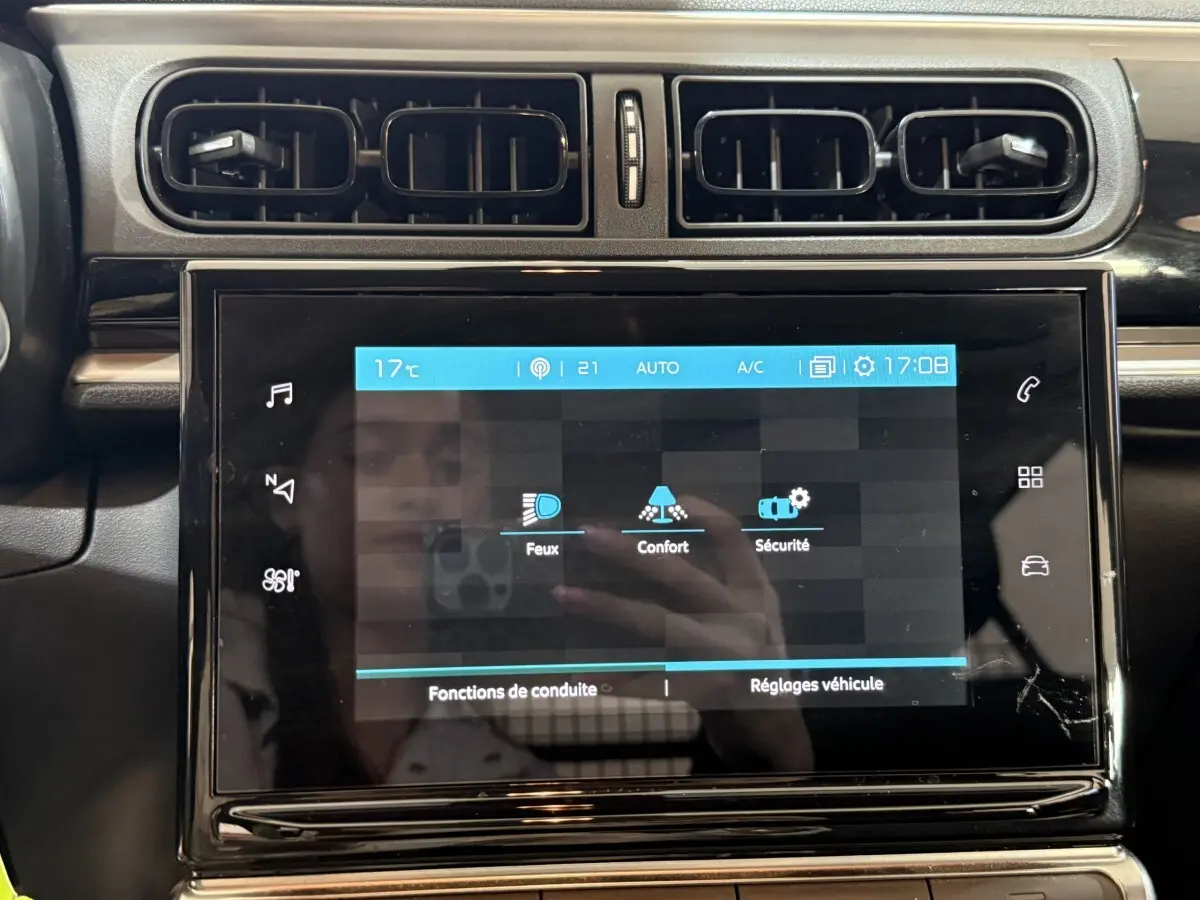 Vue rapprochée de l'écran tactile central noir du tableau de bord de la Citroën C3 blanche, affichant les réglages de conduite.