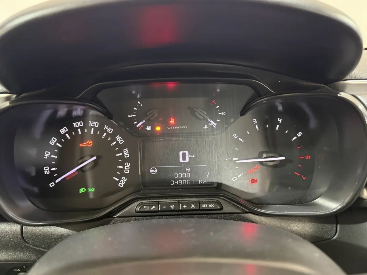 Tableau de bord de Citroën C3 blanc, affichage numérique central et compteurs analogiques en vue frontale rapprochée.