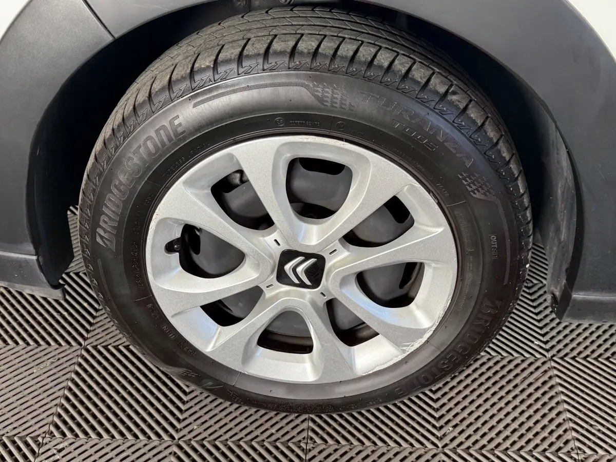 Gros plan sur la roue avant gauche d'une Citroën C3 blanche, jante argentée avec logo Citroën central.