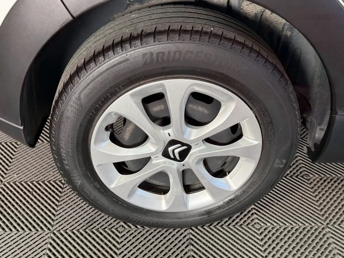 Gros plan sur la roue avant droite d'une Citroën C3 blanche, mettant en valeur la jante alliage et le logo Citroën central.