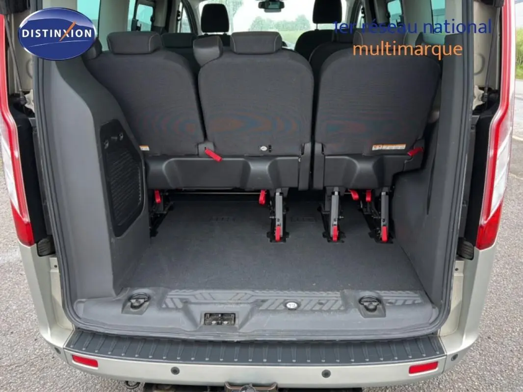 Vue arrière du Ford Tourneo Custom gris foncé, montrant l'espace de chargement et les sièges arrière rabattus.