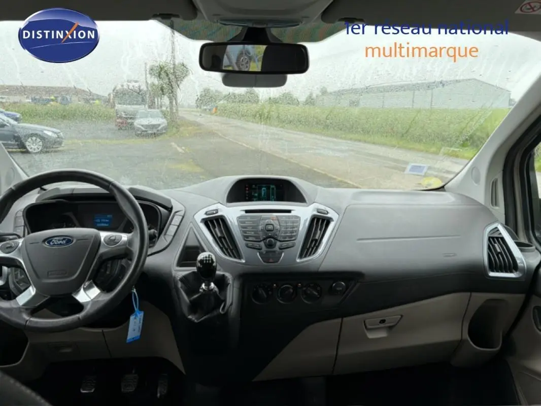 Vue intérieure du tableau de bord gris du Ford Tourneo Custom 2015 avec volant, levier de vitesse manuel et écran central.