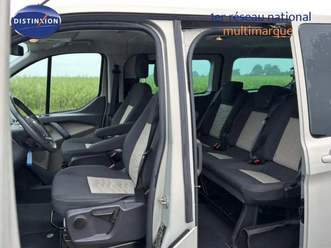 Vue intérieure côté gauche du Ford Tourneo Custom gris foncé, montrant les sièges avant et arrière avec portes ouvertes.