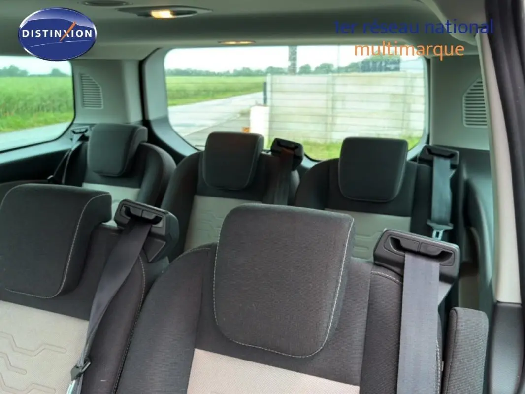 Vue intérieure arrière du Ford Tourneo Custom gris foncé, montrant les sièges passagers en tissu avec ceintures de sécurité.