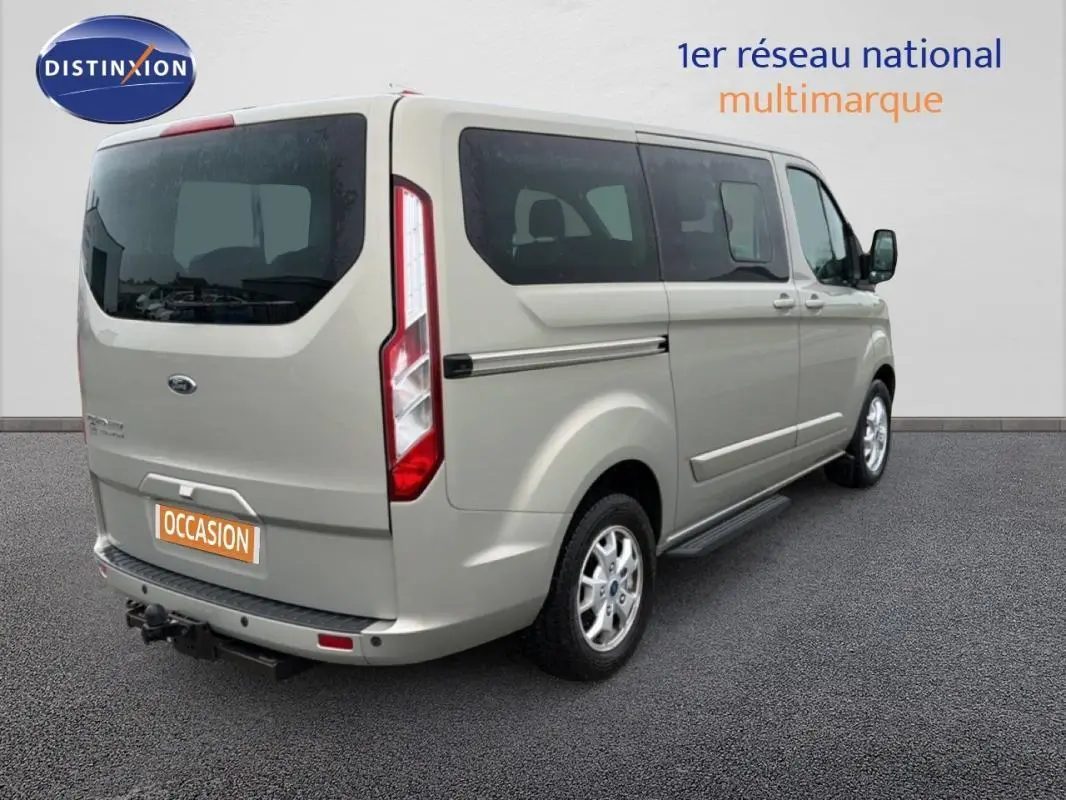 Vue 3/4 arrière droite du Ford Tourneo Custom gris foncé avec marchepieds et attelage visible.
