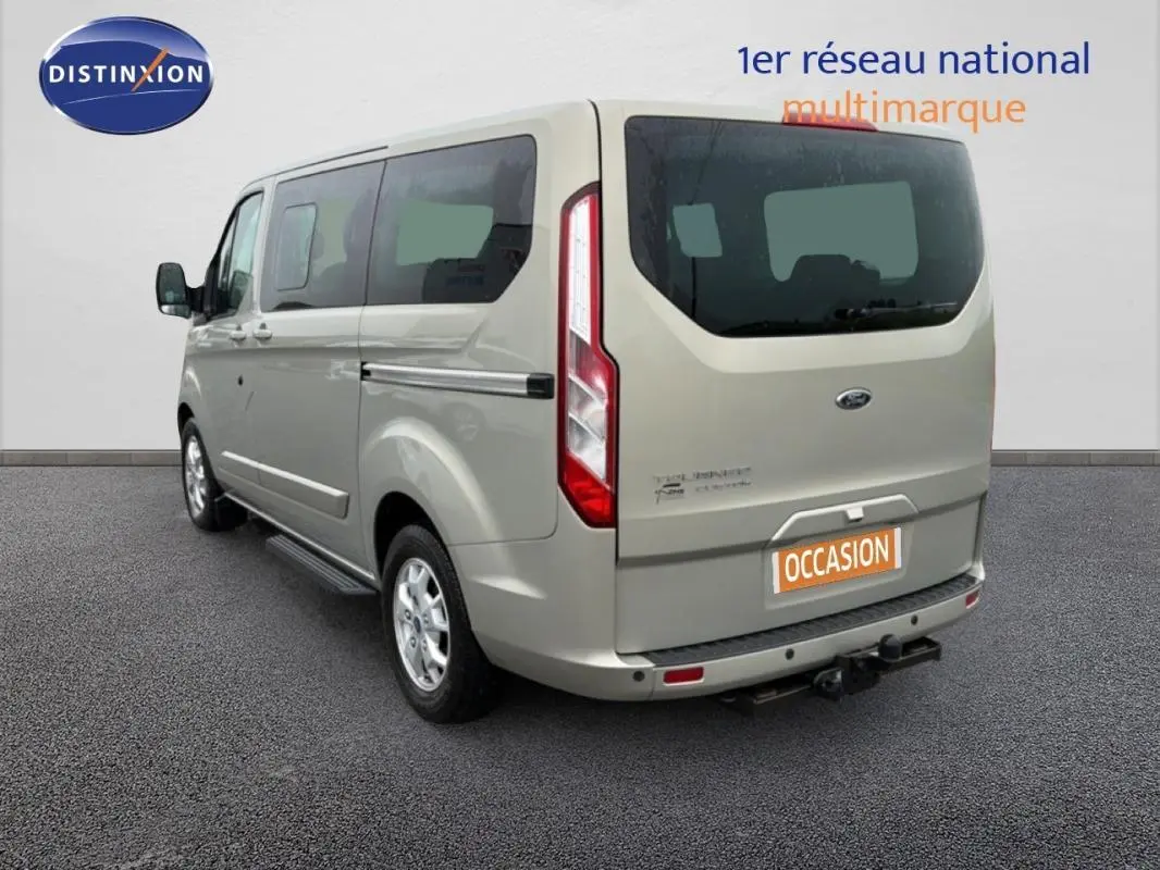 Vue 3/4 arrière droite d’un Ford Tourneo Custom gris clair avec attelage et vitres surteintées.