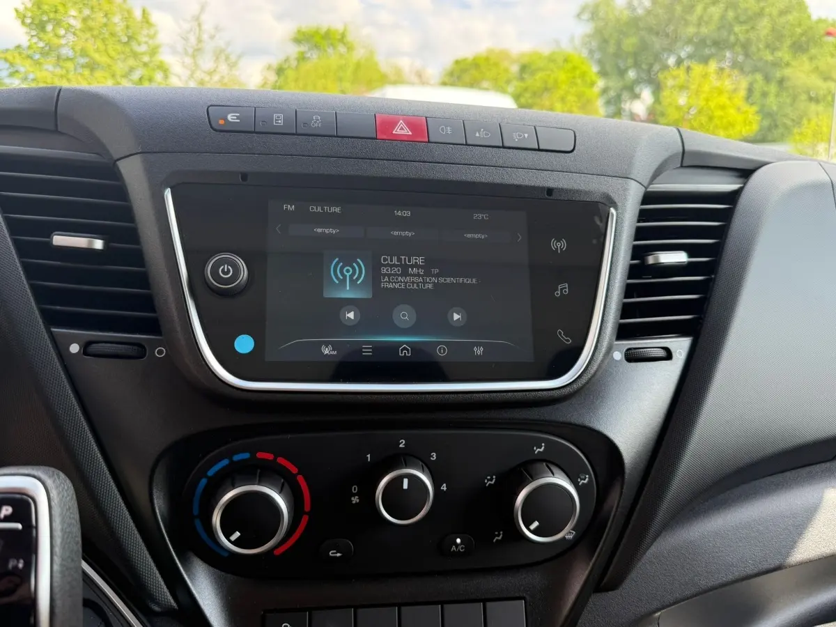 Vue rapprochée de la console centrale noire de l'IVECO Daily 35S18 2026 avec écran tactile et commandes de climatisation.