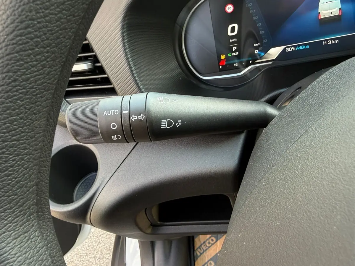 Gros plan sur la manette de commande des phares et clignotants du tableau de bord du Daily blanc IVECO 2026.