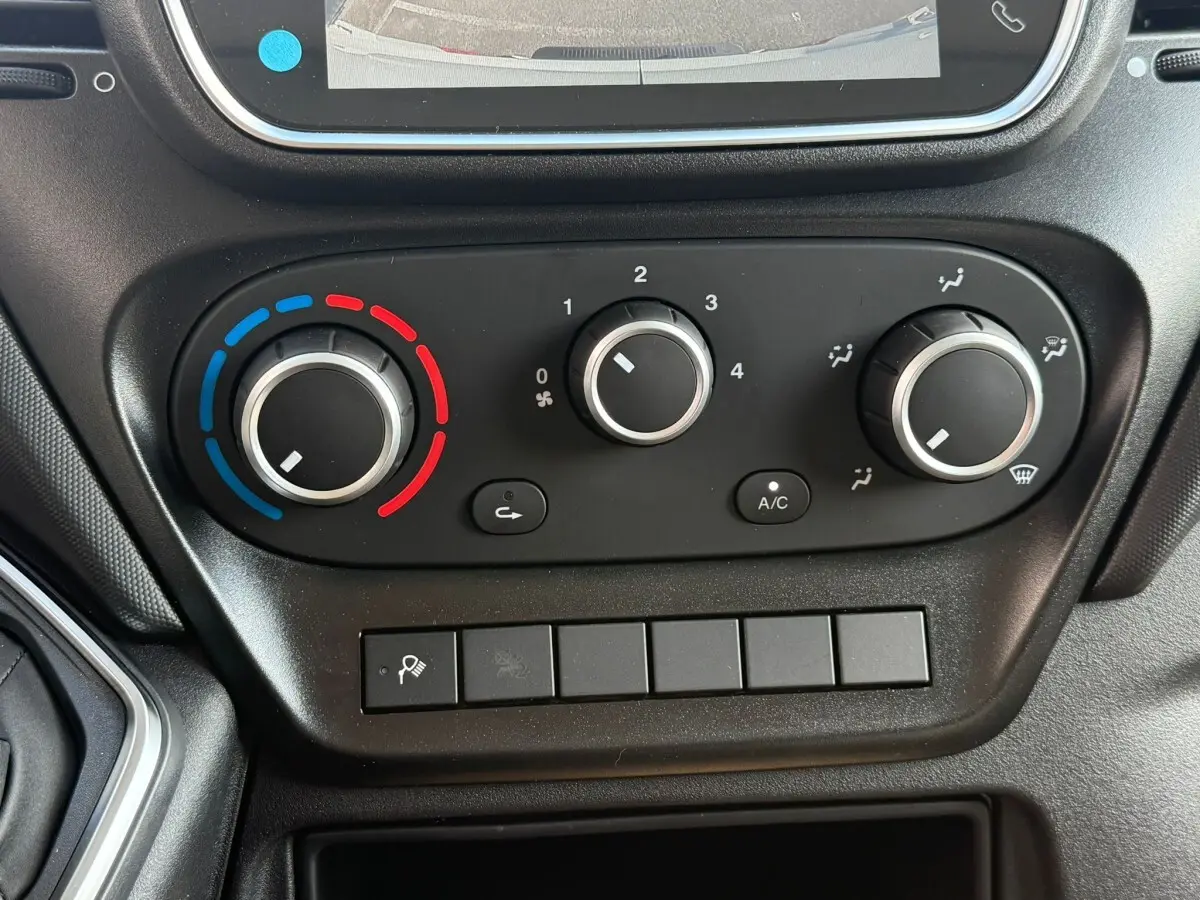 Gros plan sur les commandes de climatisation manuelle du tableau de bord noir du Iveco Daily blanc, version 2026.