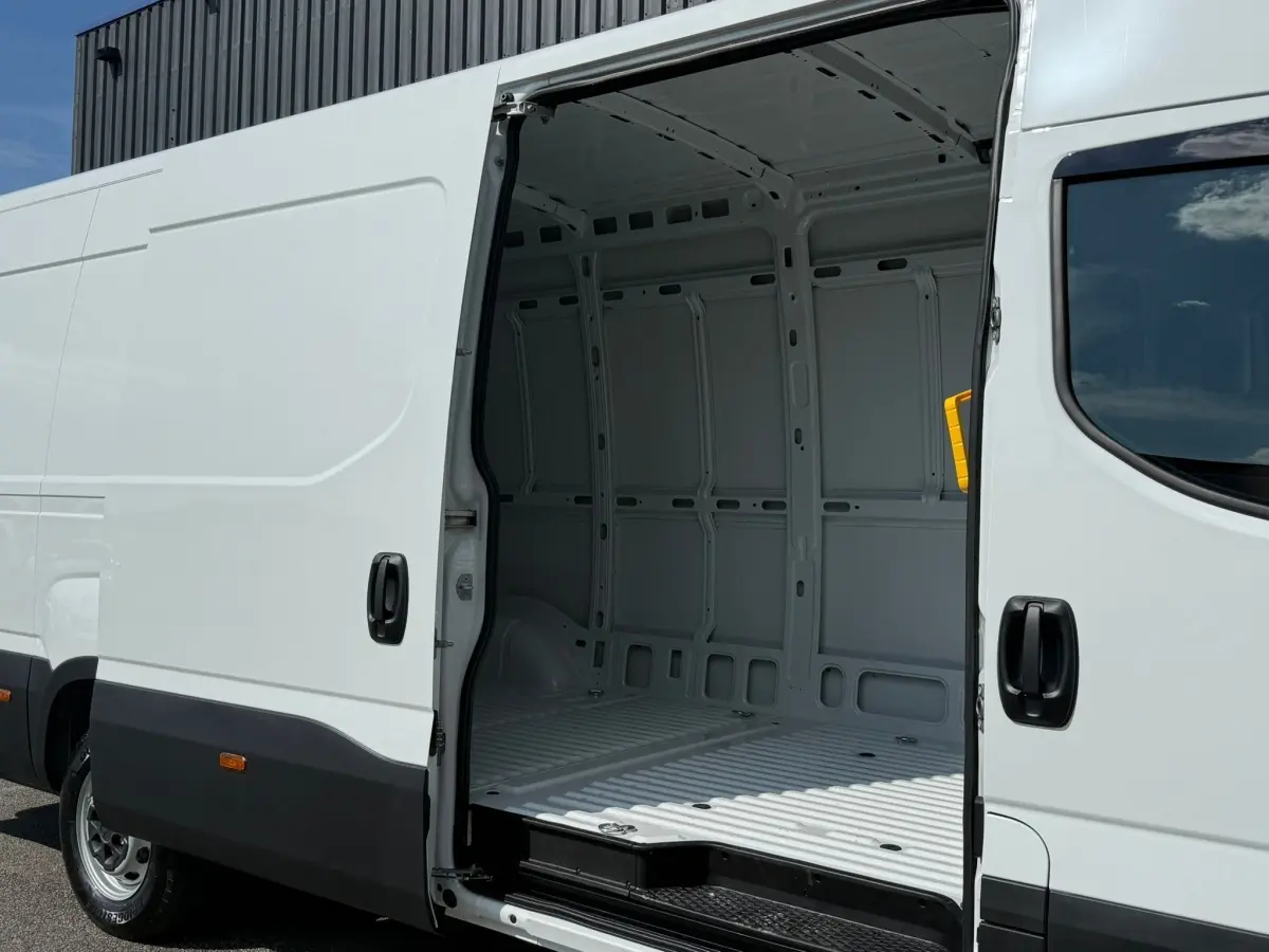 Vue latérale gauche d’un Iveco Daily blanc 2026 avec porte coulissante ouverte montrant l’intérieur vide du fourgon.