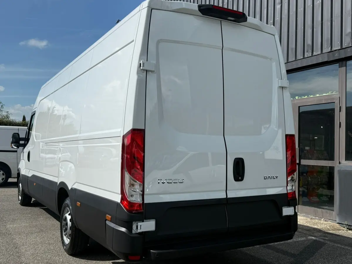 Vue arrière droite d’un utilitaire Iveco Daily blanc avec portes arrière fermées et feux rouges visibles.