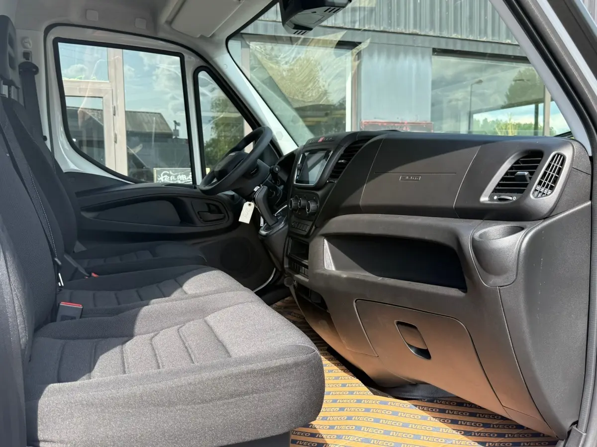 Vue intérieure côté droit du poste de conduite du fourgon blanc Iveco Daily 35S18 2026 avec tableau de bord noir et sièges gris.