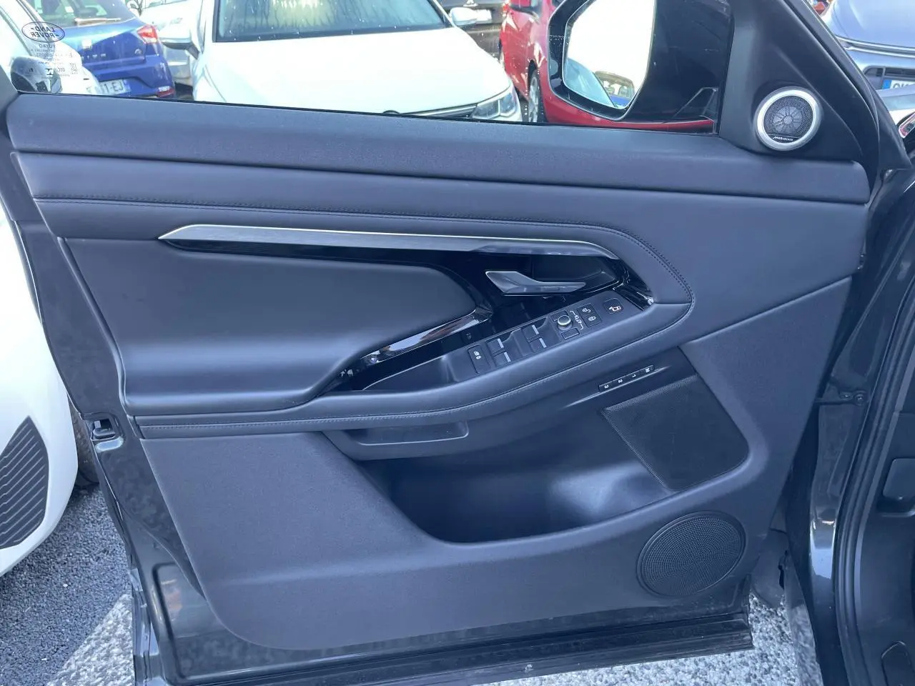 Porte côté gauche du Range Rover Evoque gris, avec commandes électriques et haut-parleur intégré visible.