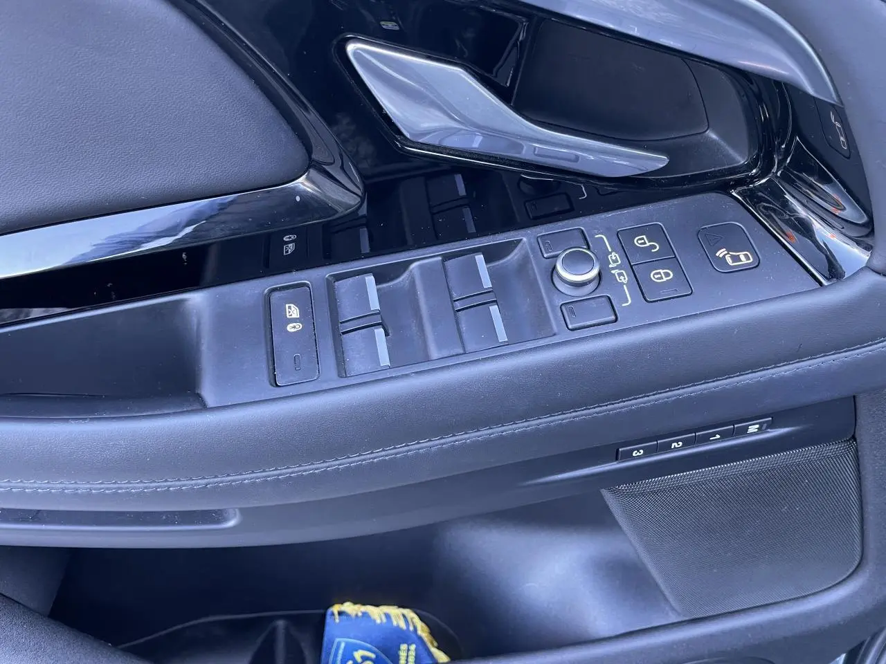 Gros plan sur la porte côté conducteur du Range Rover Evoque gris, montrant les commandes des vitres et la poignée intérieure chromée.