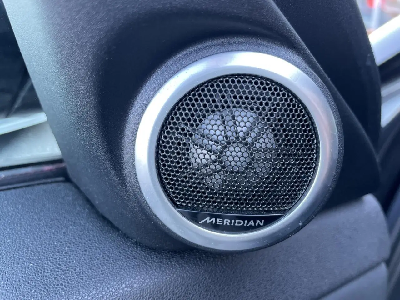 Gros plan sur le haut-parleur Meridian noir et argenté côté gauche dans l'habitacle du Range Rover Evoque gris 2019.