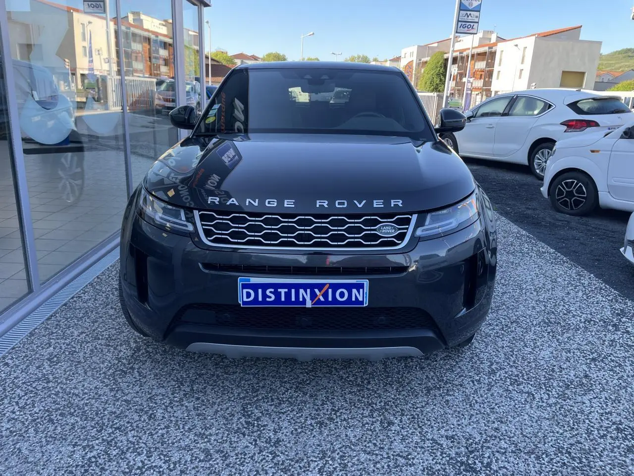 Vue frontale d'un Range Rover Evoque gris métallisé avec calandre Dark Atlas et logo Land Rover visible.