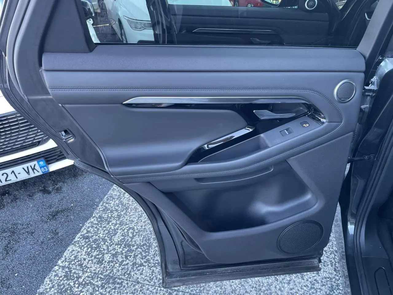 Porte arrière gauche ouverte du Range Rover Evoque gris, avec garniture intérieure en cuir et commandes de fenêtre.